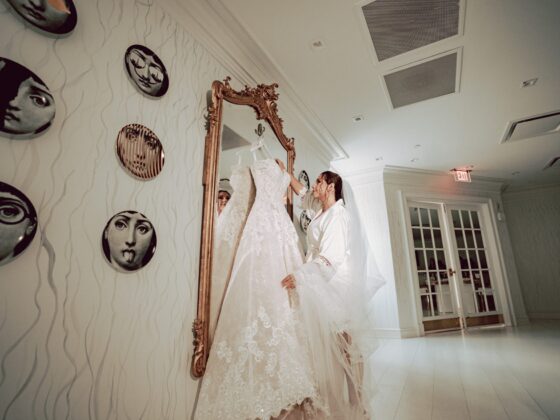 Bride looks at her wedding dress hanging on a gold mirror in the Penthouse Suite.