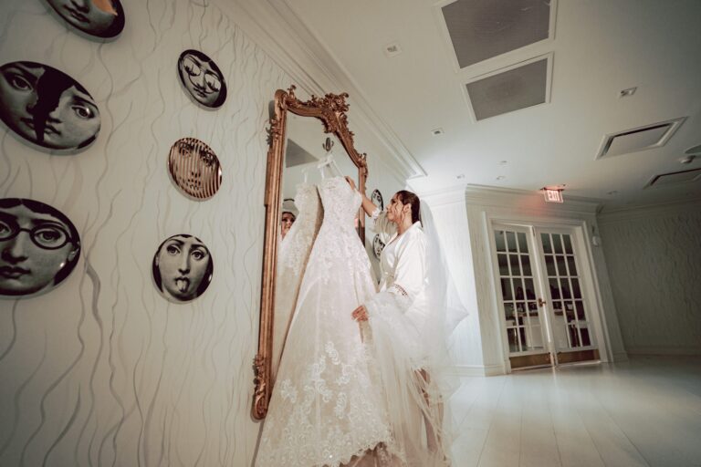 Bride looks at her wedding dress hanging on a gold mirror in the Penthouse Suite.