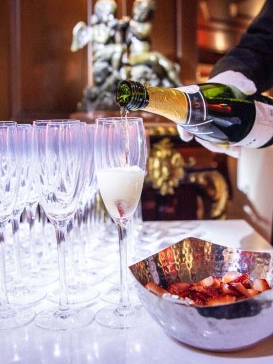 Waiter pours champagne into elegant flute glasses.
