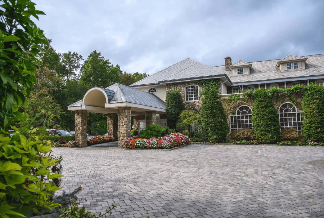 Front view of Crystal Plaza, a luxurious and historic mansion with a stone facade, green ivory embellishments, and a well-manicured garden.