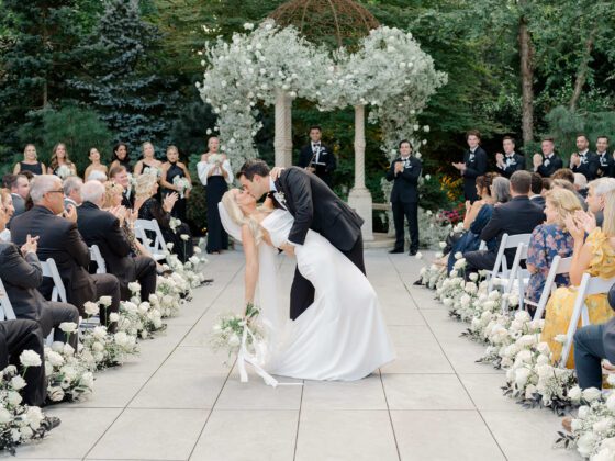 Groom kisses bride as they walk down aisle as a just married couple.