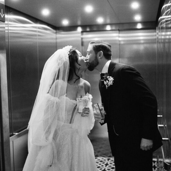 Bride and groom kiss in the elevator.