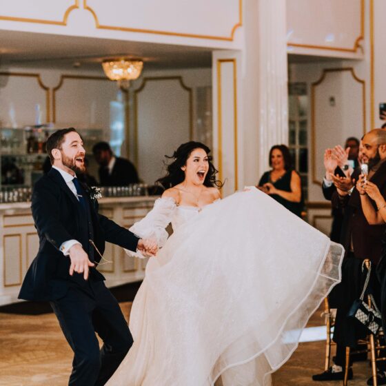 Bride and groom excitedly run onto dance floor during their entrance into the grand ballroom at Crystal Plaza.