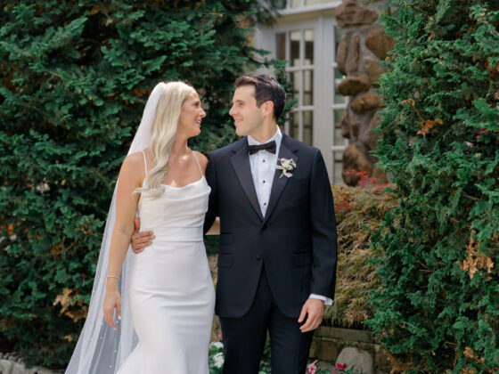 Bride and groom look at each other in front of Crystal Plaza's stone walls filled with greenery.