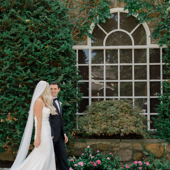 Bride and groom walk in front of window.