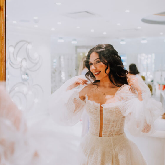Bride smiles and looks in mirror as she gets ready in Crystal Plaza's Penthouse Suite.
