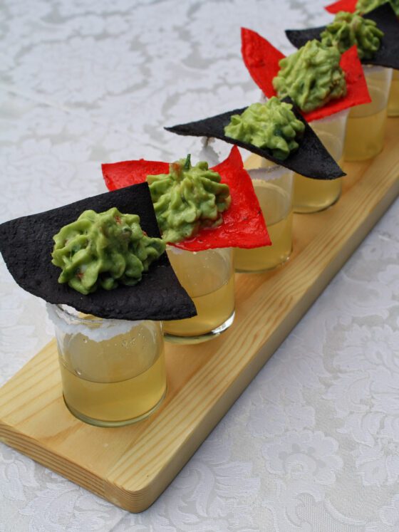 Shots with tortilla chips topped with guacamole.