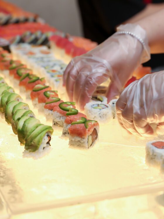 Chef places freshly rolled sushi on ice bar.