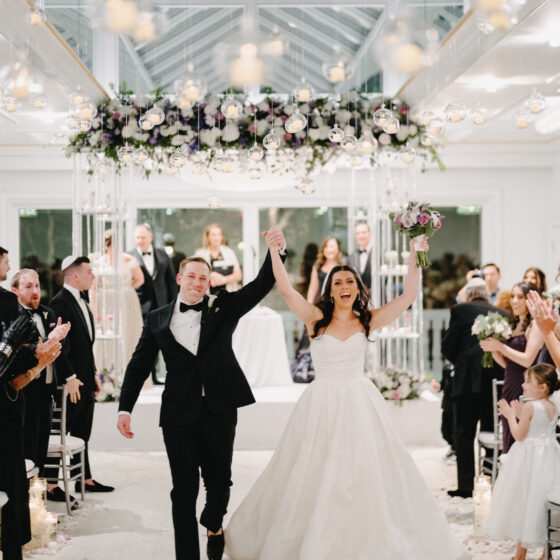 Bride and groom walk down aisle with excitement as just married couple.