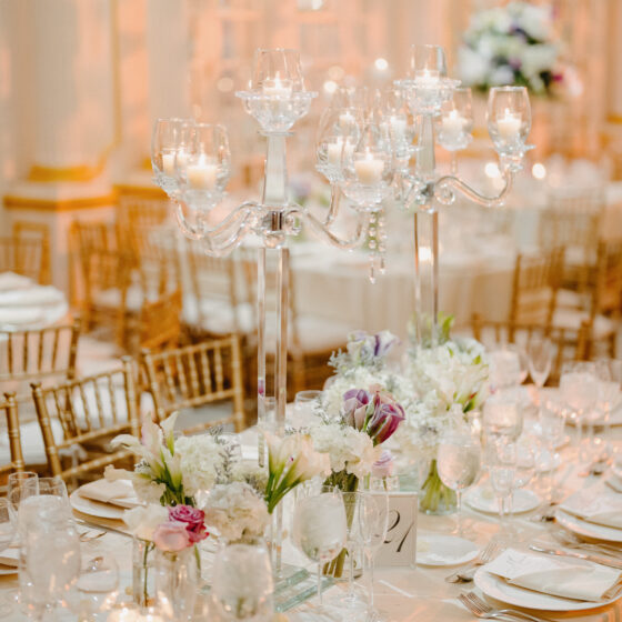 Romantic wedding table decor with crystal candelabras and delicate white and pink flowers in tiny vases.