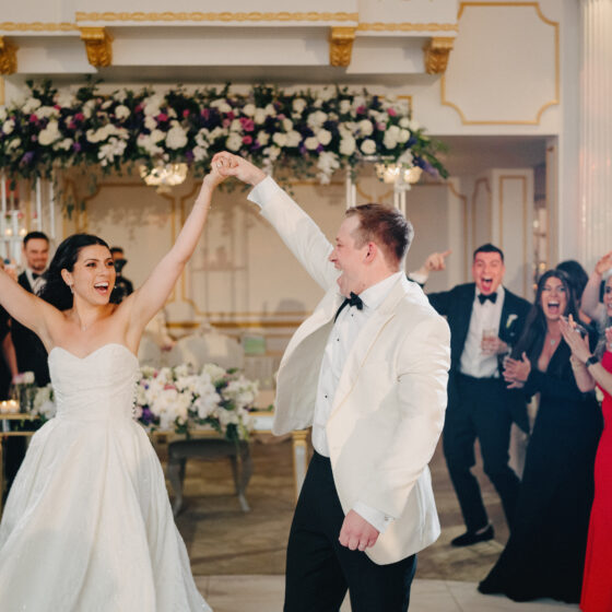 Bride and groom hold hands and raise them during first entrance to wedding reception.