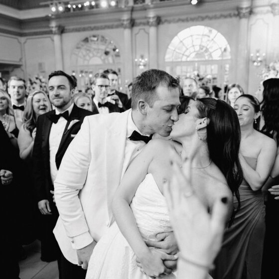Black and white image of bride and groom kissing on dance floor.