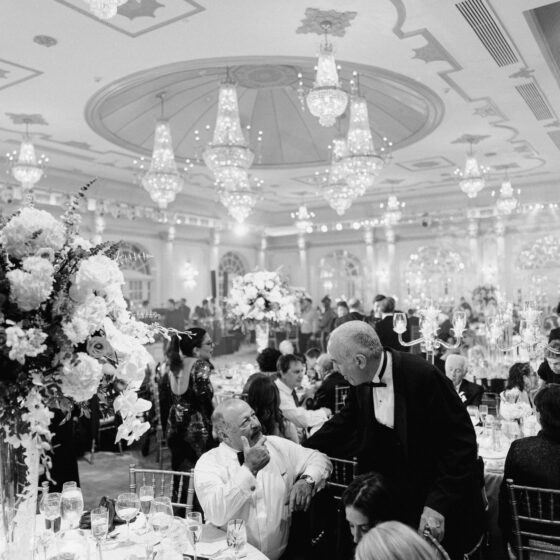 Black and white image of guests mingling at wedding reception in Crystal Plaza's grand ballroom.
