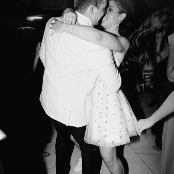Black and white photo of bride and groom dancing on dance floor.