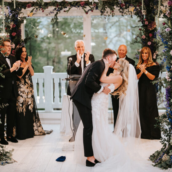Bride and groom kiss as a just married couple underneath a stunning floral chuppah in Crystal Plaza's Atrium.