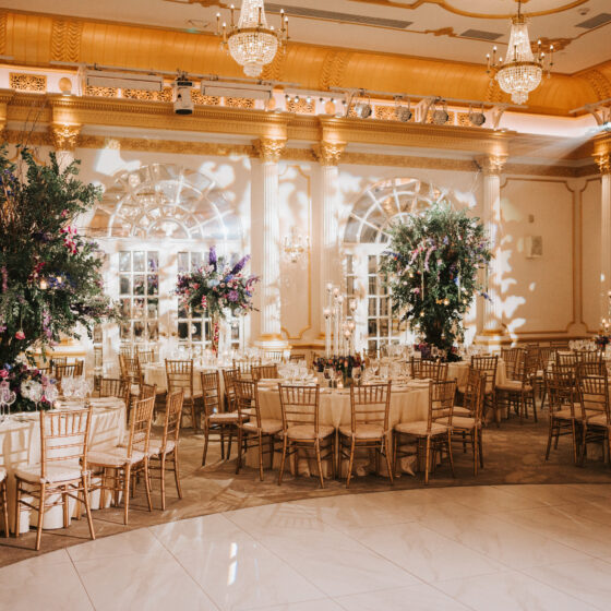 Wedding reception tables decorated with lush tree centerpieces filled with delicate flower accents.