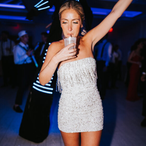 Bride drinks cocktail on the dance floor of the wedding after party in a mini strapless sparkle dress.