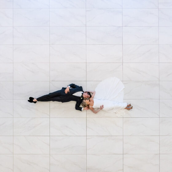 Overview shot of bride and groom laying on dance floor.