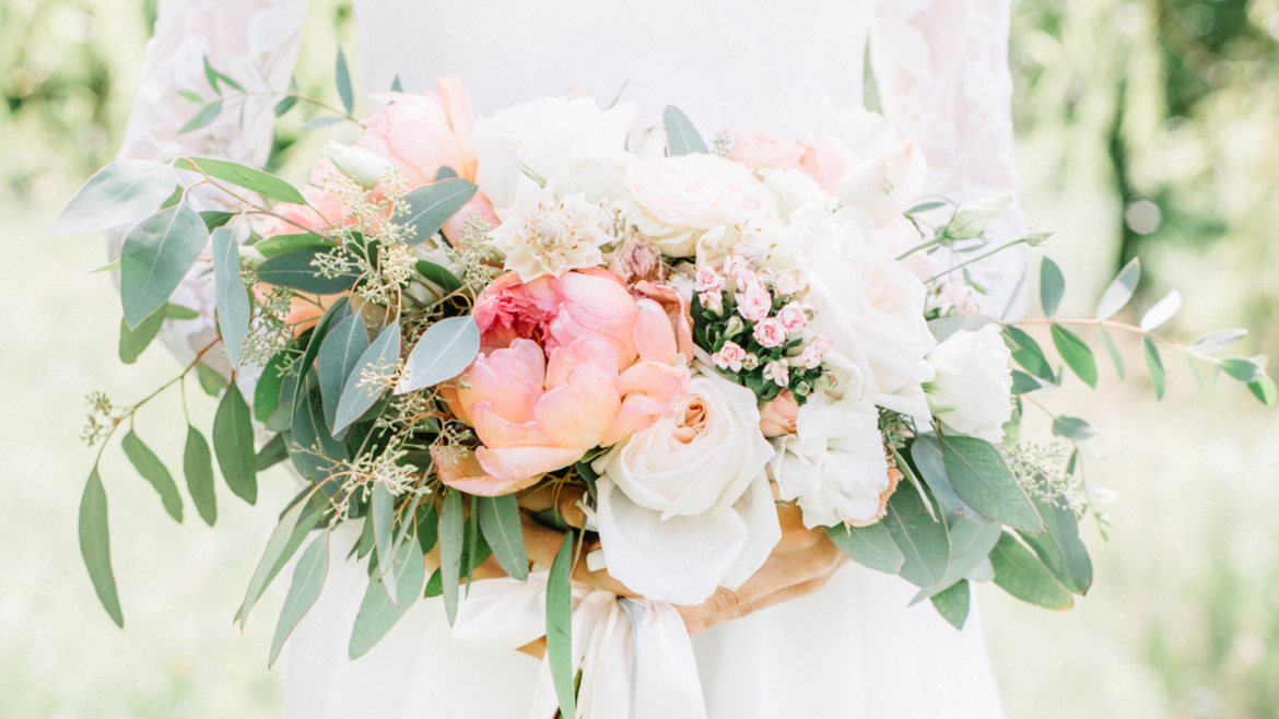 Bridal bouquet filled with pink peonies, white roses, and greenery.