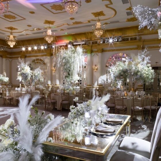 Elegant white flower and feather wedding reception decor, complemented by gold accents.