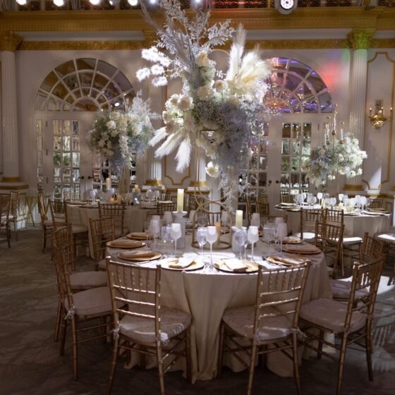 Elegant white flower and feather wedding reception decor, complemented by gold table settings.