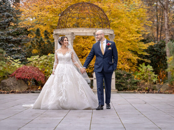 Bride and groom pose for photo during the fall in Crystal Plaza's garden.