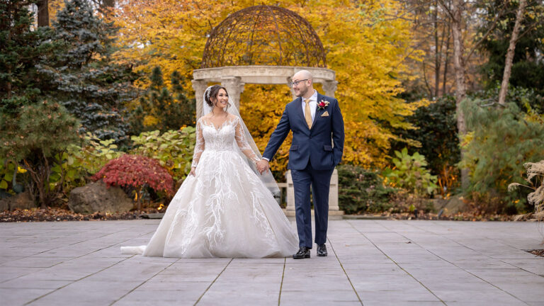 Bride and groom pose for photo during the fall in Crystal Plaza's garden.