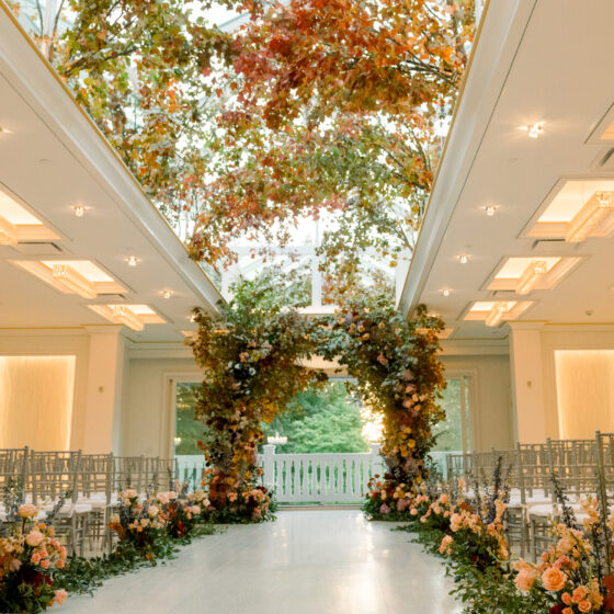 The Atrium decorated in fall flowers, leaves, and branches for a wedding ceremony.