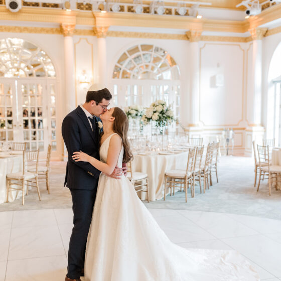 Bride and groom kiss in Crystal Plaza's grand ballroom.