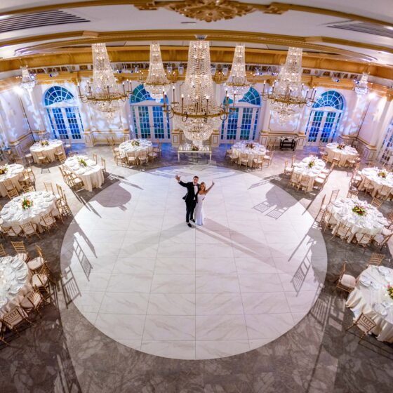 Overview shot of bride and groom standing in center of Crystal Plaza's grand ballroom, decorated for the wedding reception.