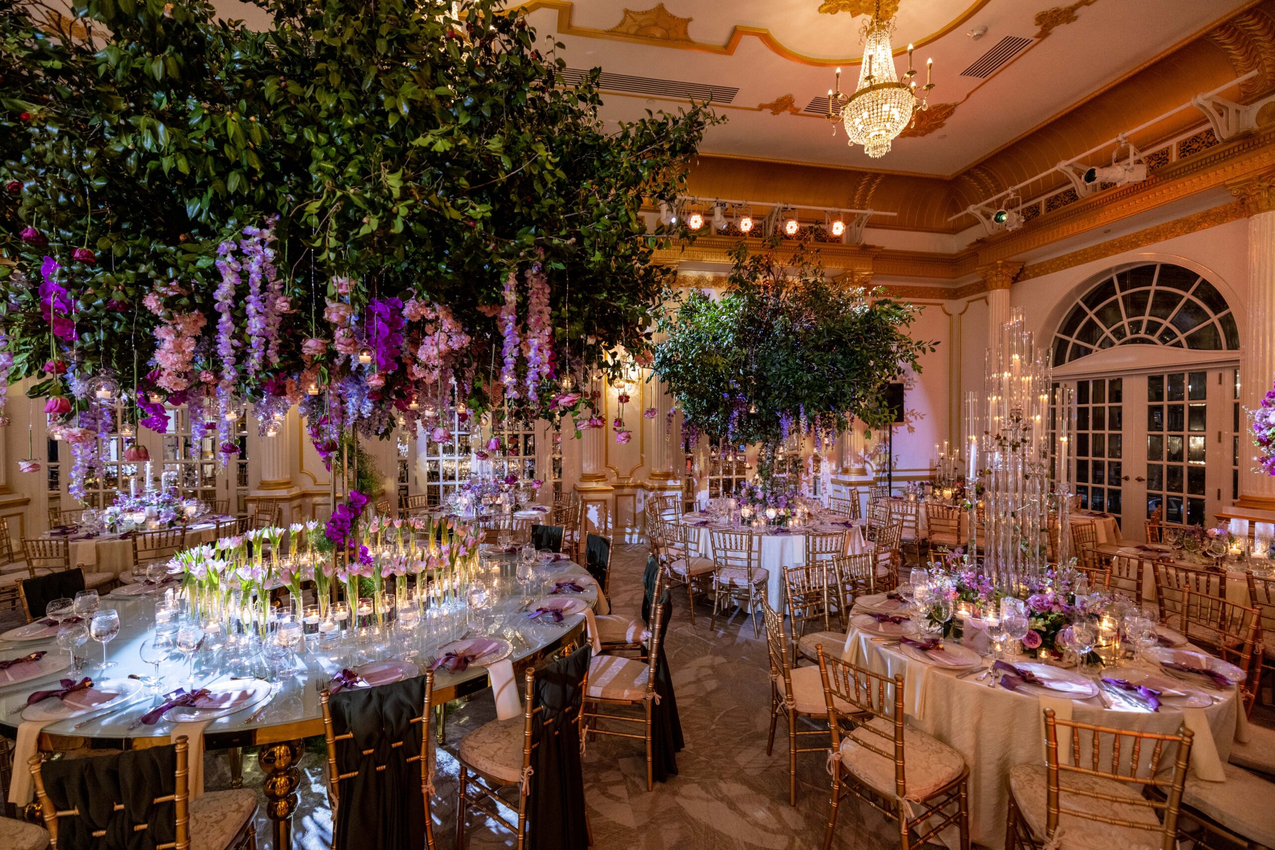 Elegant wedding tree table centerpieces complemented by pink and purple flowers and candles.