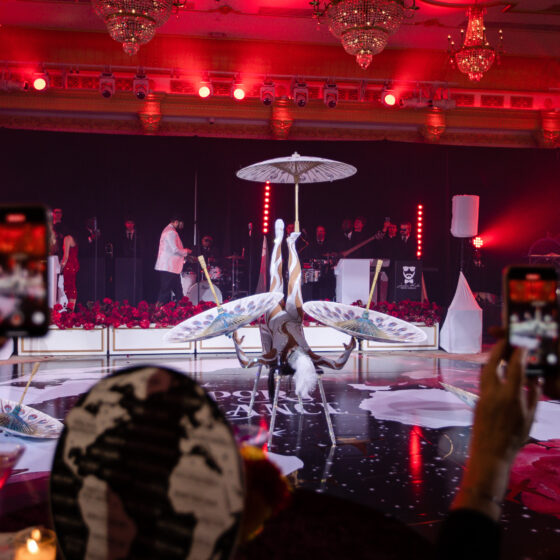 Acrobatic artist spins umbrellas on dance floor at Crystal Plaza's Passport to Romance event.