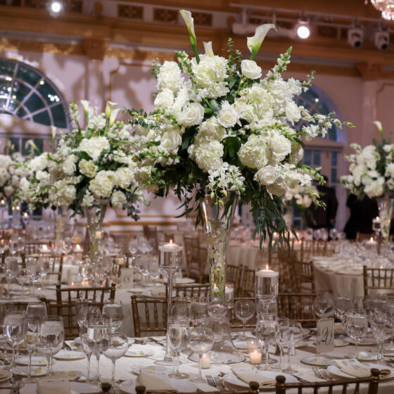 Classic white wedding centerpieces filled with roses, hydrangeas, and lilies.