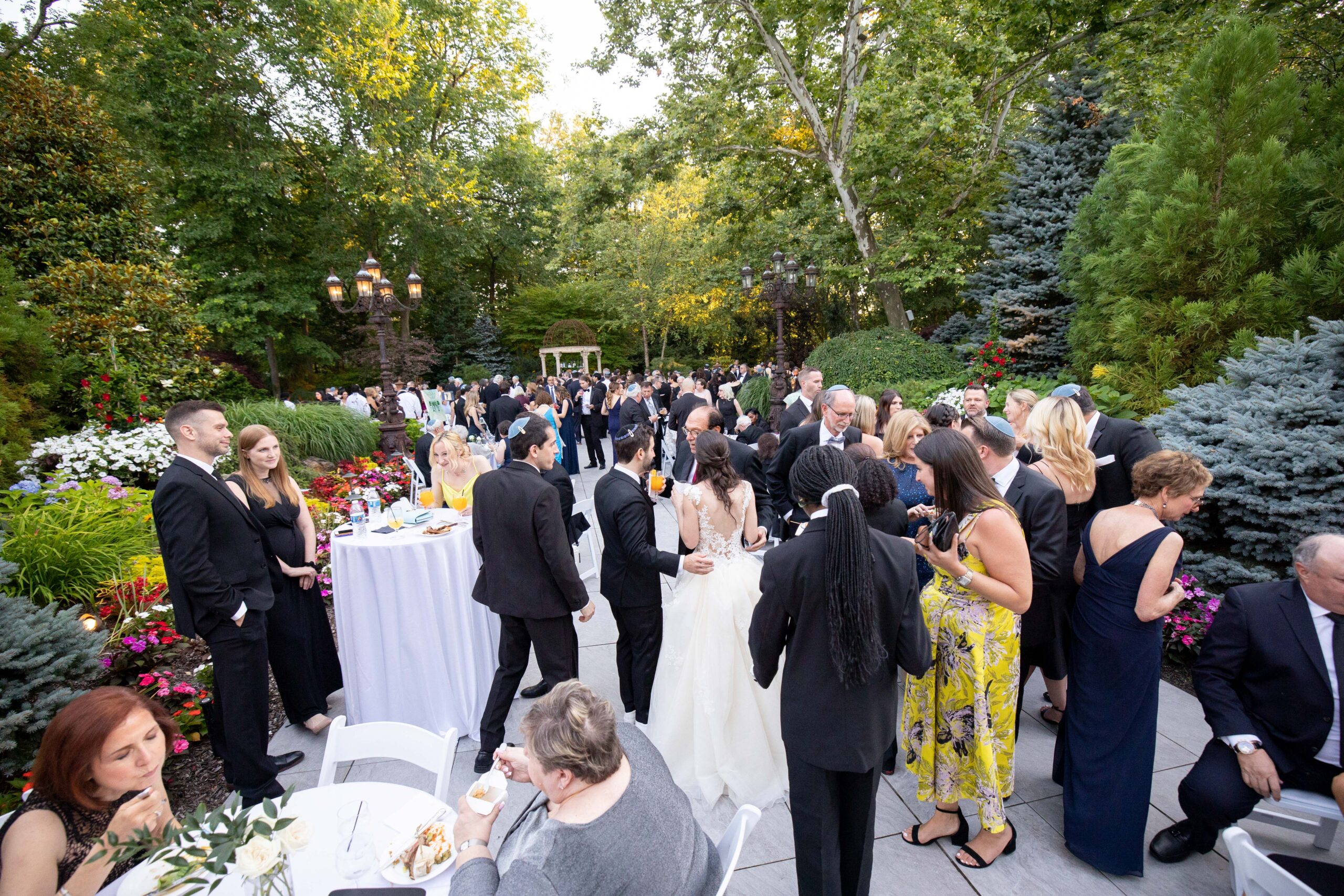 Bride, groom, and guests mingle during cocktail hour in the lush Gardens at Crystal Plaza.