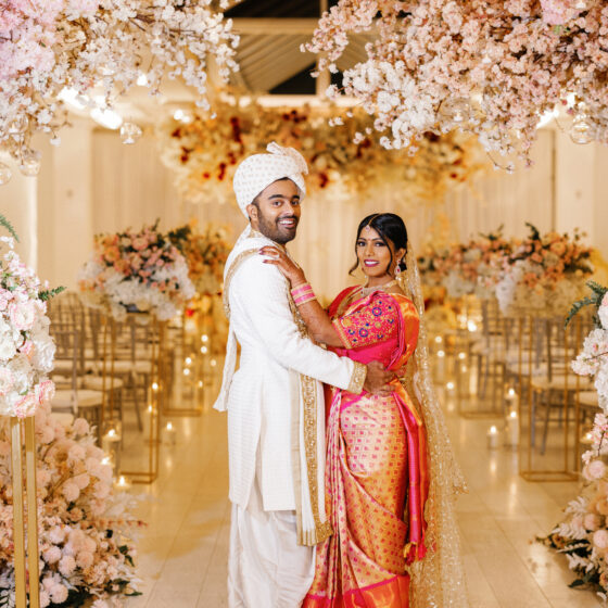 Bride and groom smile amongst beautiful pink and white flowers, decorated elegantly throughout Crystal Plaza's Atrium.
