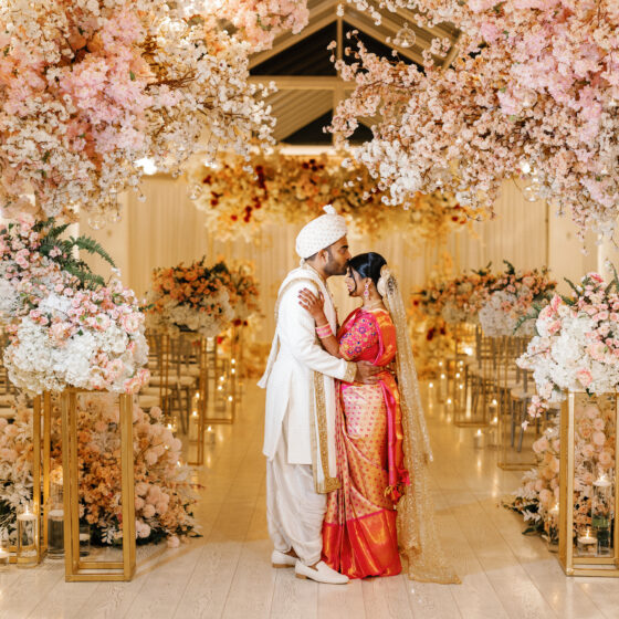 Bride and groom embrace amongst beautiful pink and white flowers, decorated elegantly throughout Crystal Plaza's Atrium.