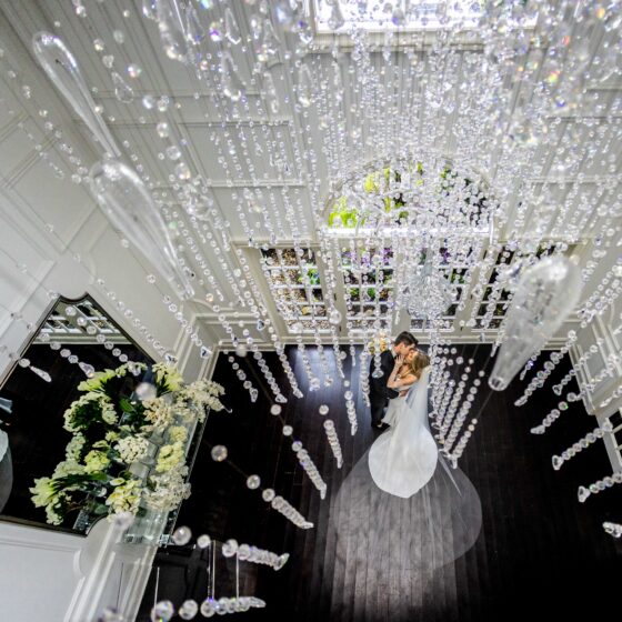 Bride and groom kiss underneath crystal chandelier at Crystal Plaza.