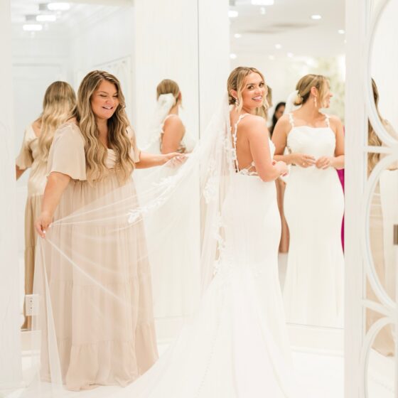 Bride smiles as her maid of honor holds her veil in Crystal Plaza's Penthouse Suite.