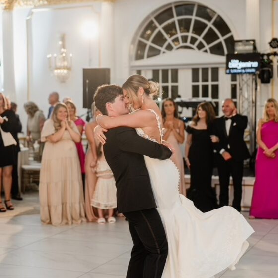 Groom picks up bride on dance floor during first dance.