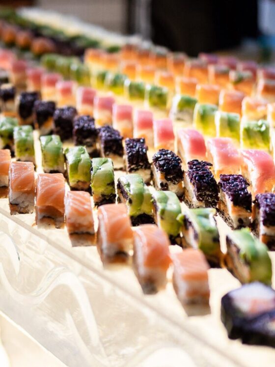 Rainbow sushi lined up on an ice bar.