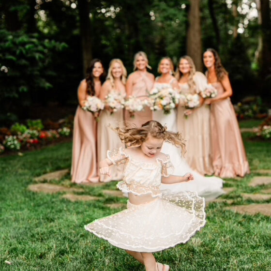 Flower girl dances in front of bride and bridal party.